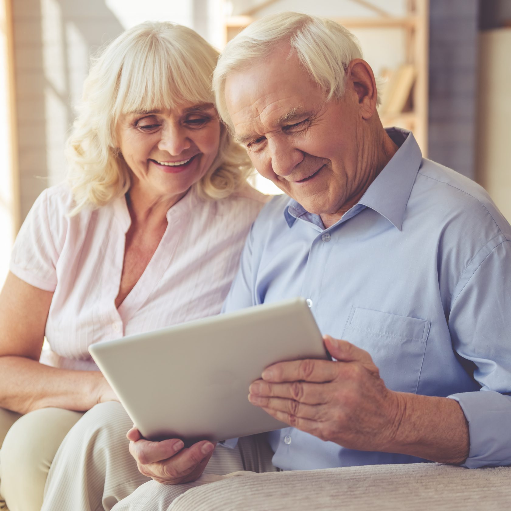 Linsenmodelle – Augenarzt Dr. Claus Thimm in Neuss Beautiful old couple is using a digital tablet and smiling while sitting on couch at home